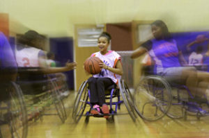 A group of girls playing basketball in wheel chairs. 