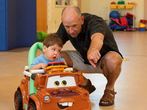 Todler in toy car with counselor