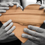 helping hands holding a wooden heart